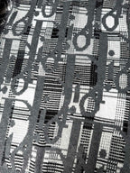 Close-up of gray knit sweater with dense black-and-white logo graphic pattern