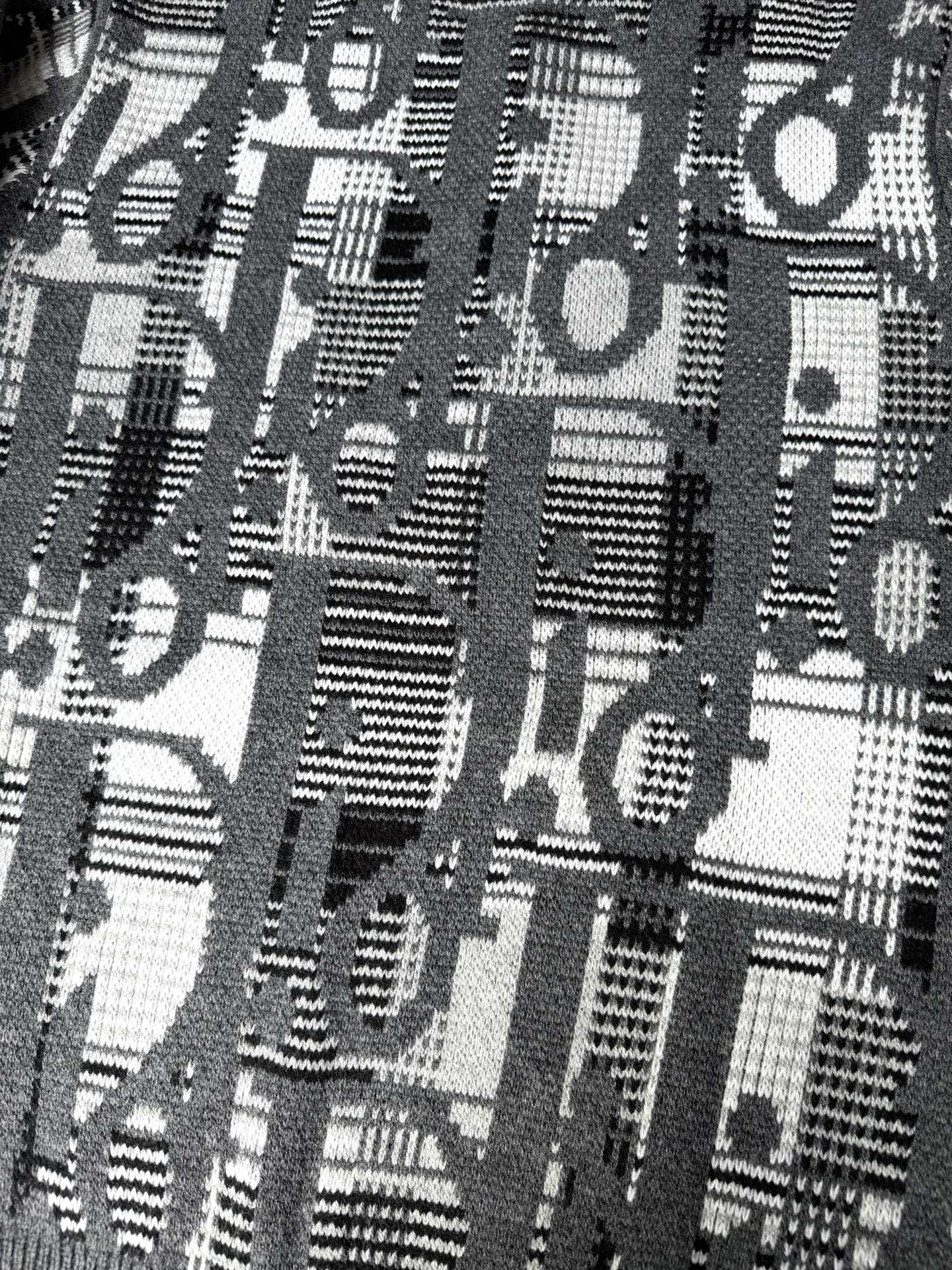 Close-up of gray knit sweater with dense black-and-white logo graphic pattern