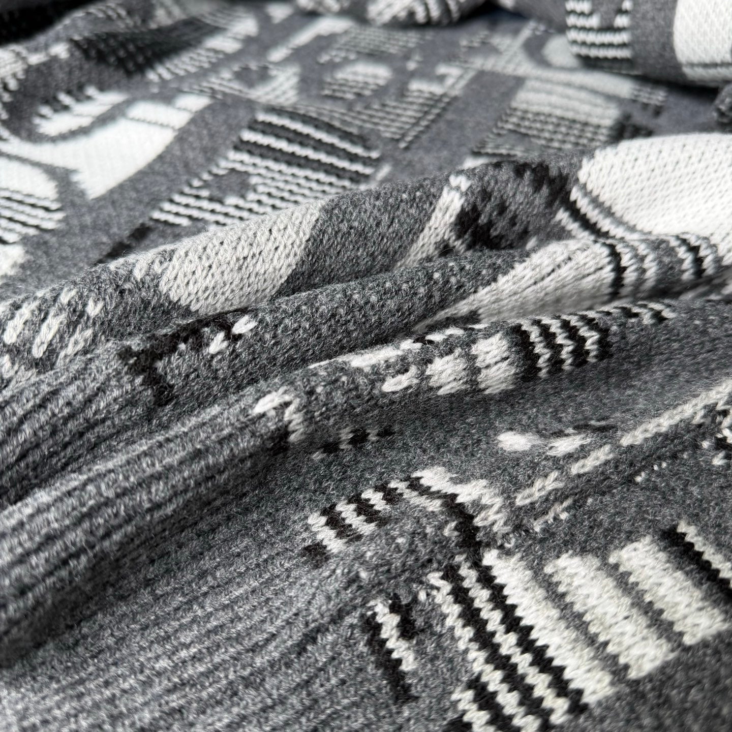 Gray knit fabric with black-and-white geometric and logo-style pattern