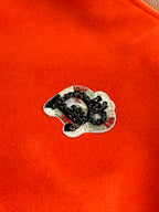 Orange fabric varsity jacket with embroidered crest patch on chest