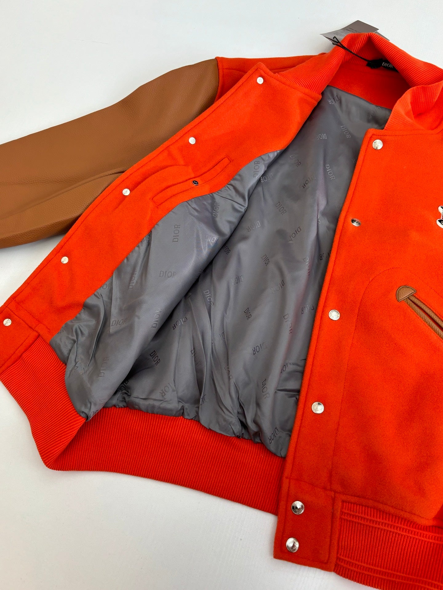 Orange varsity jacket with snap front and open lining, ribbed hem visible