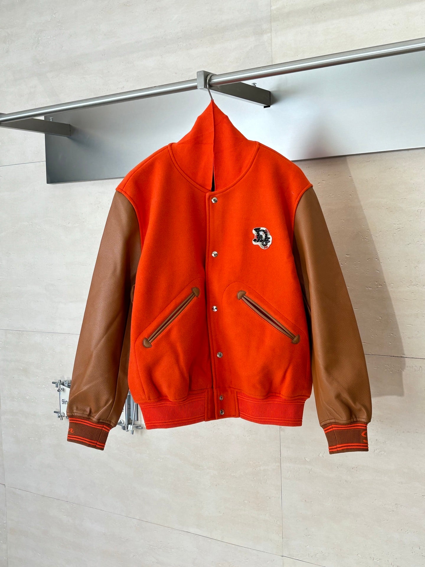Orange varsity jacket with brown leather-look sleeves, snap front, crest patch