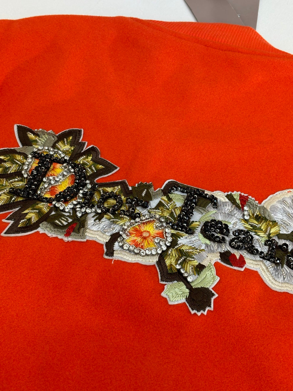 Orange jacket front with dense ornate embroidered applique across the chest