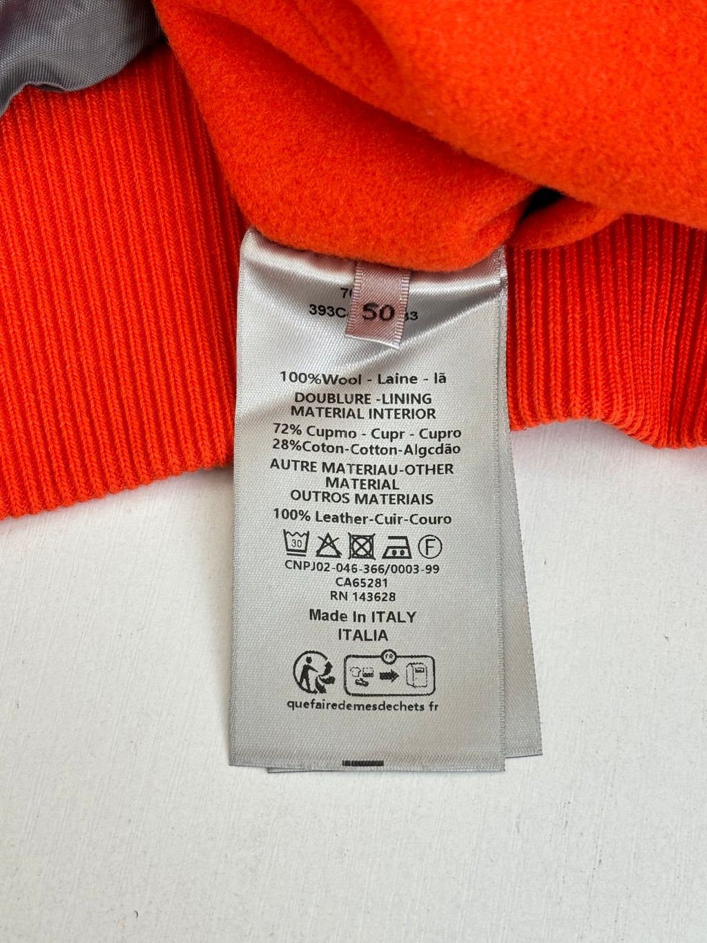 Orange jacket neck label and care tag showing 100% wool and leather