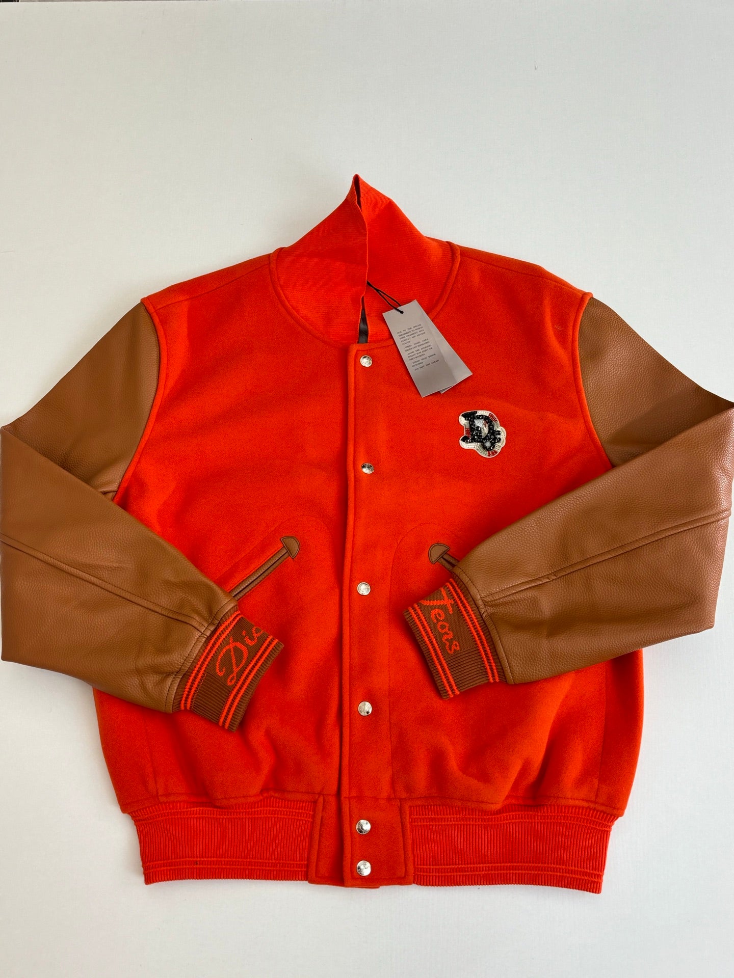 Orange varsity jacket with brown leather-look sleeves, snap front, embroidered crest