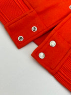 Orange ribbed cuffs and hem with silver snap buttons on varsity jacket