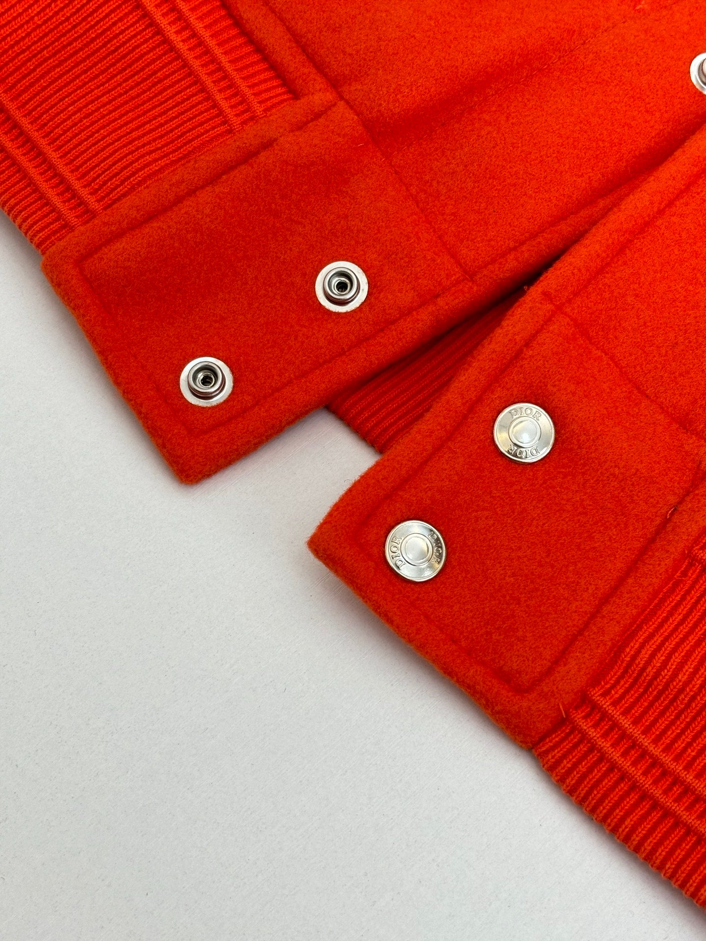 Orange ribbed cuffs and hem with silver snap buttons on varsity jacket