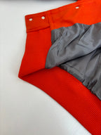 Orange varsity jacket with gray inner lining and ribbed cuffs, snap placket