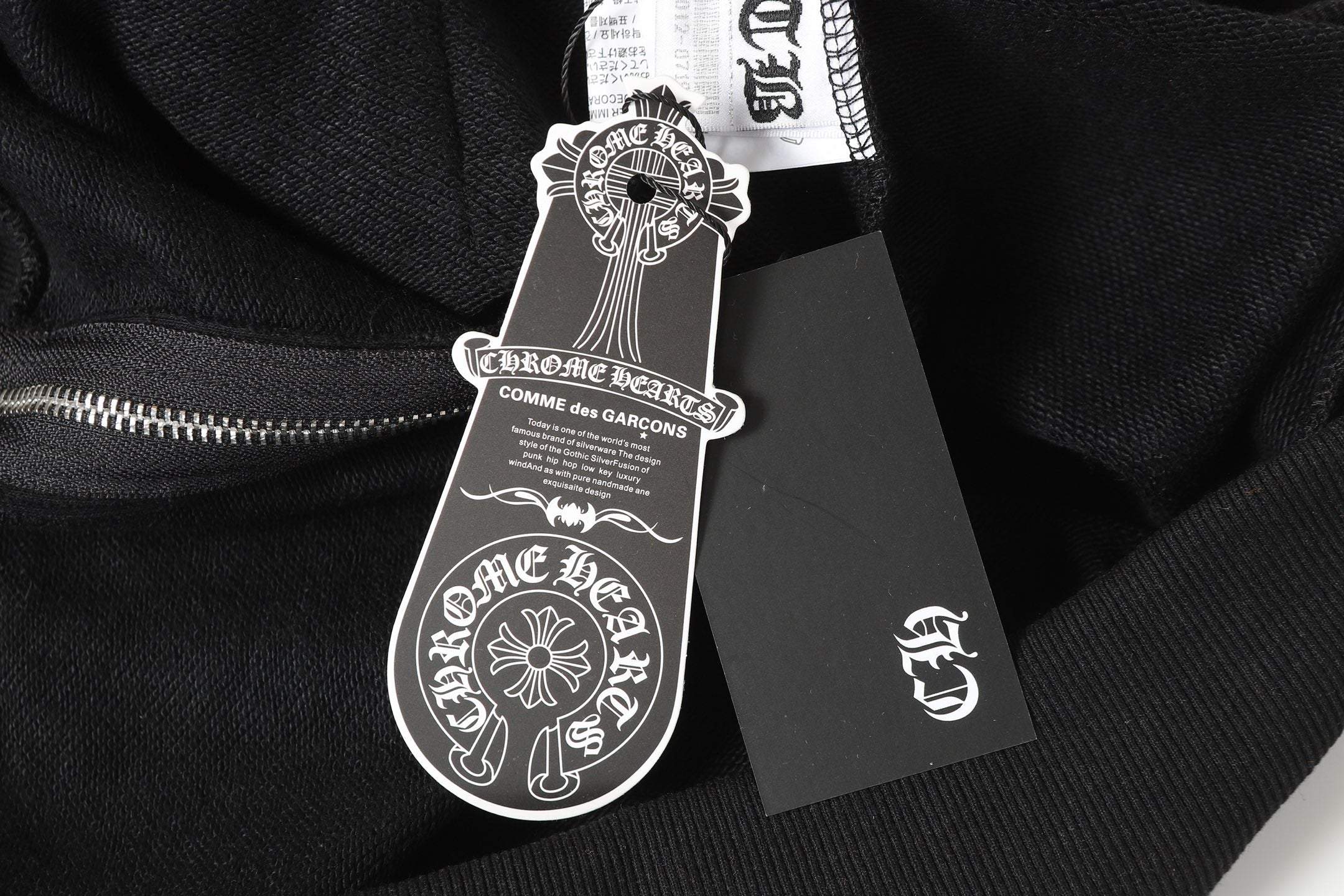 Black long-sleeve top with dangling brand hang tag