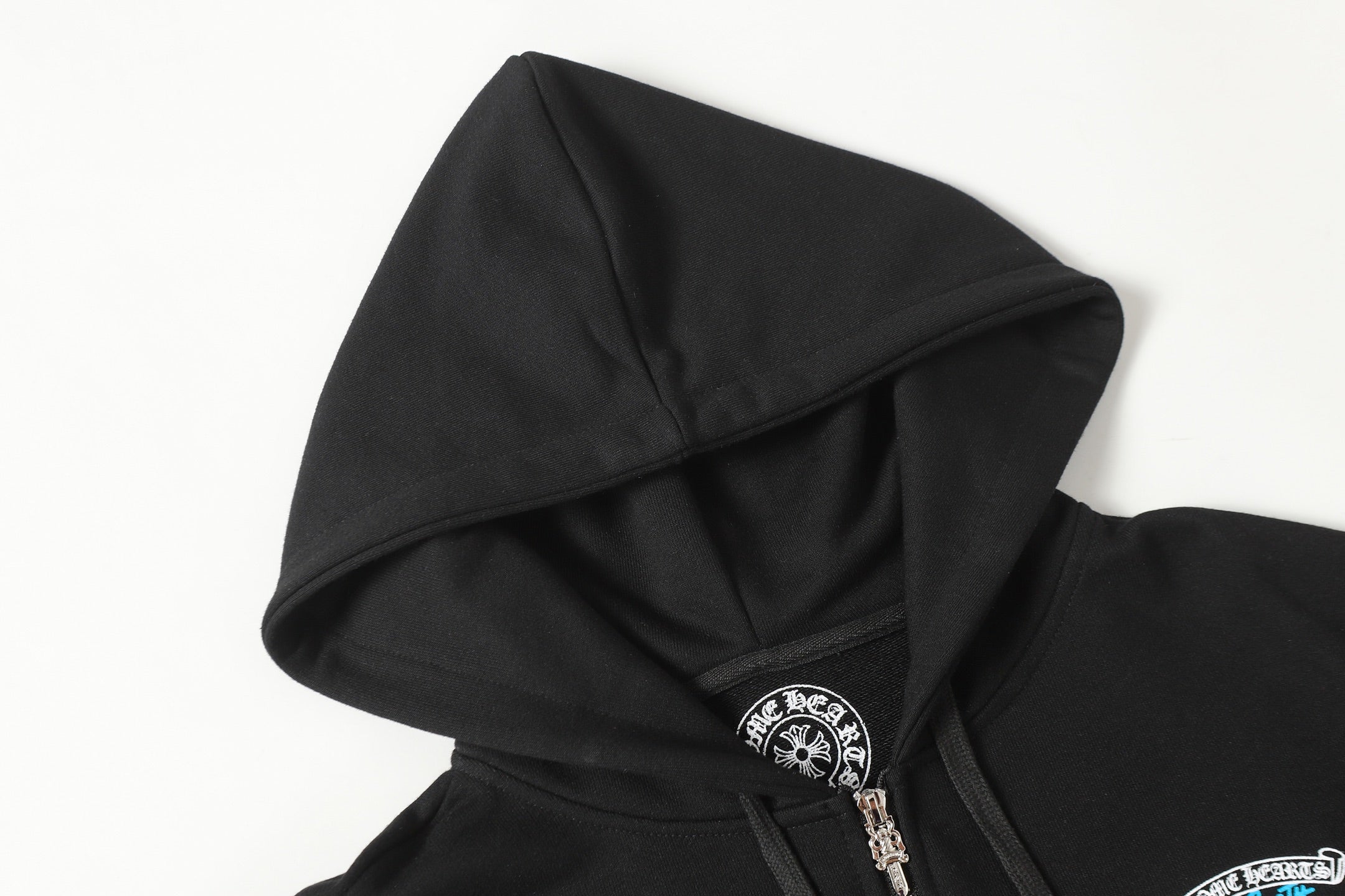 Black zip-up hoodie hood with drawstring and metal zipper pull detail.