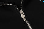 Black hoodie close-up of front zipper with shiny metal pull and teeth.