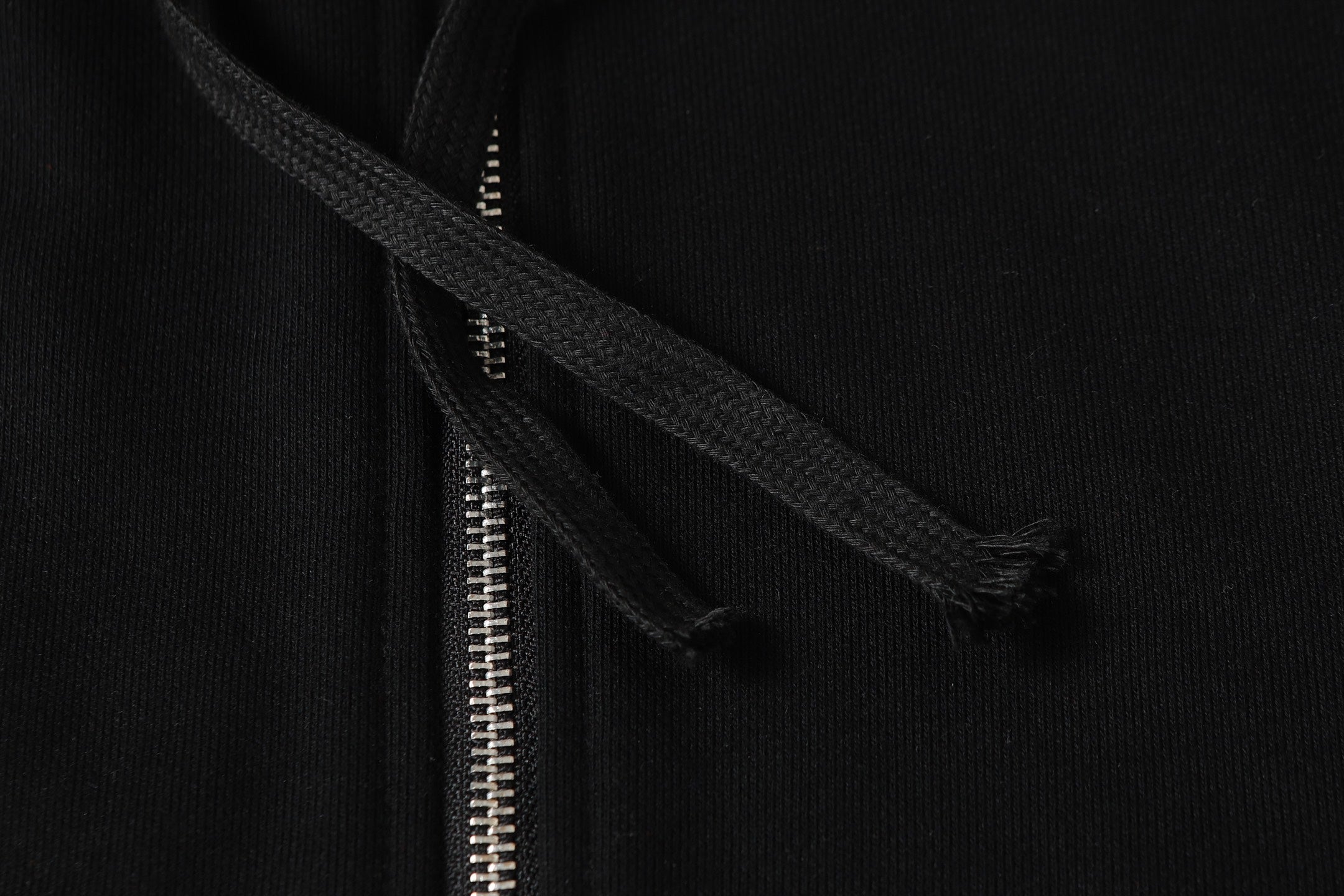 Black hoodie close-up of neckline and zipper track with hood seam.