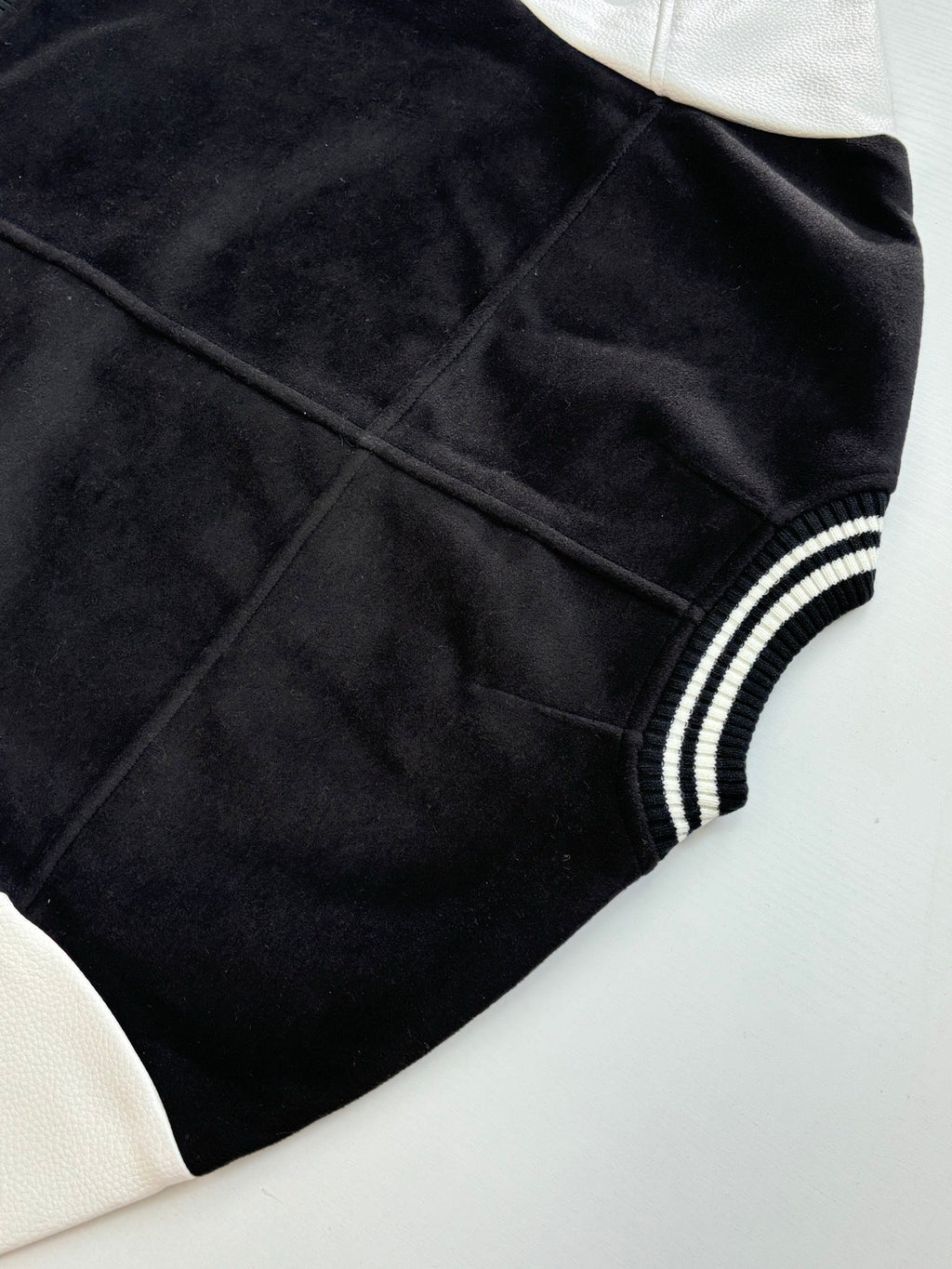 Louis Vuitton varsity jacket side view with smooth black fabric and ribbed striped collar cuff