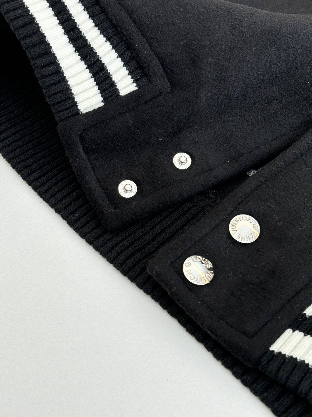 Louis Vuitton varsity jacket hem and button placket close-up with ribbed striped details