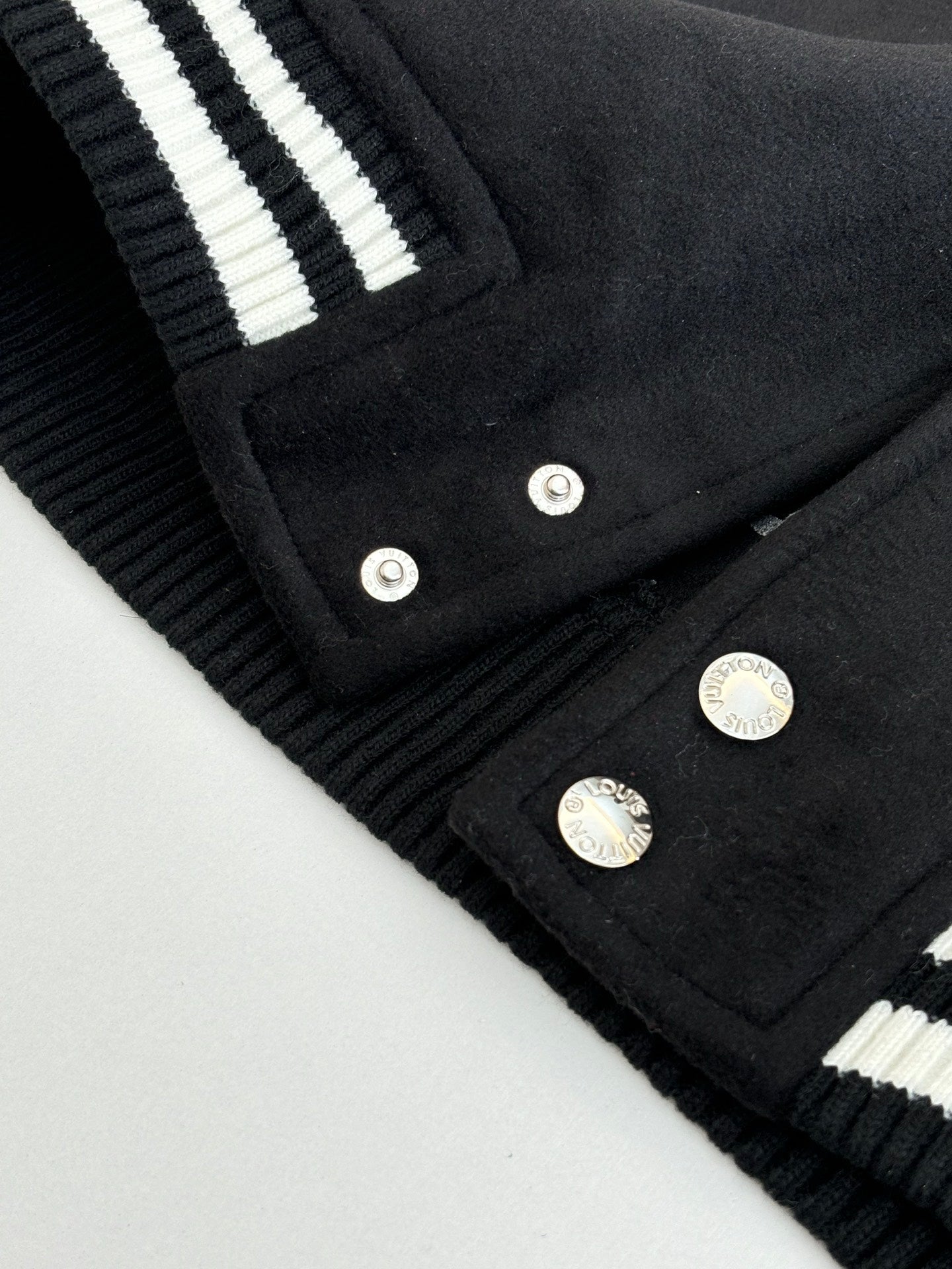 Louis Vuitton varsity jacket hem and button placket close-up with ribbed striped details