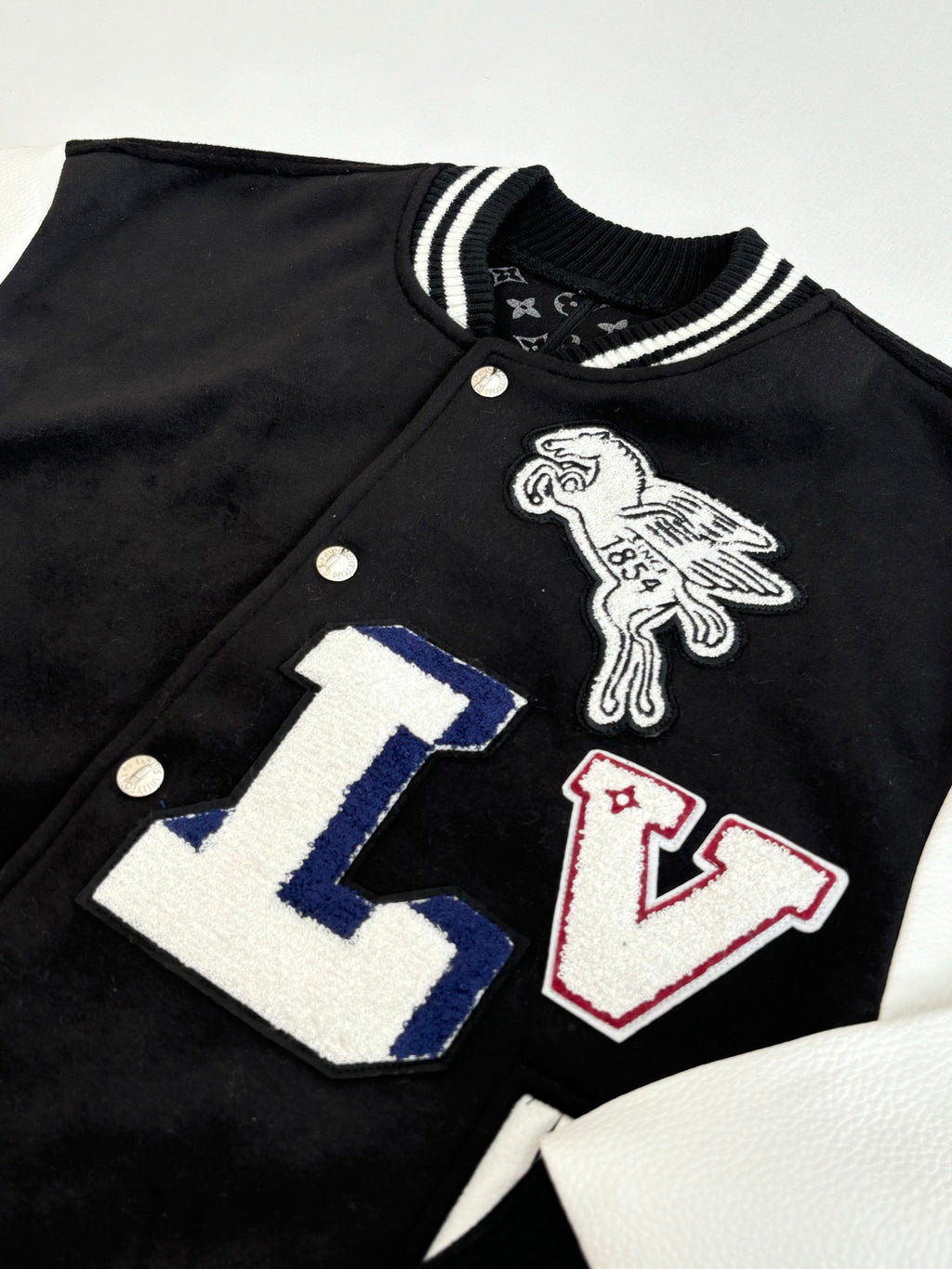 Louis Vuitton varsity jacket close-up with colorful LV letter graphic and bird emblem