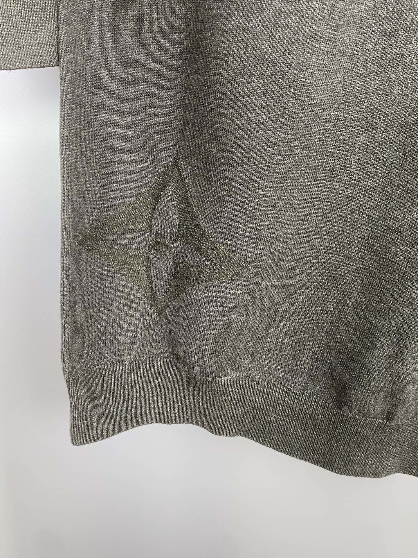 Grey knit sweater hem with subtle allover logo pattern, close-up