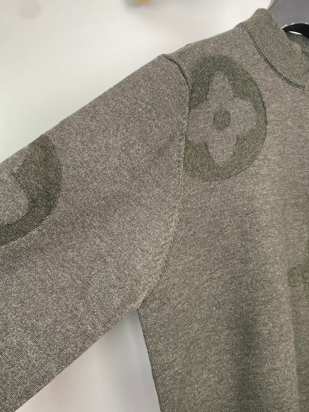 Grey knit sweater with allover logo pattern, long sleeves, angled view on hanger