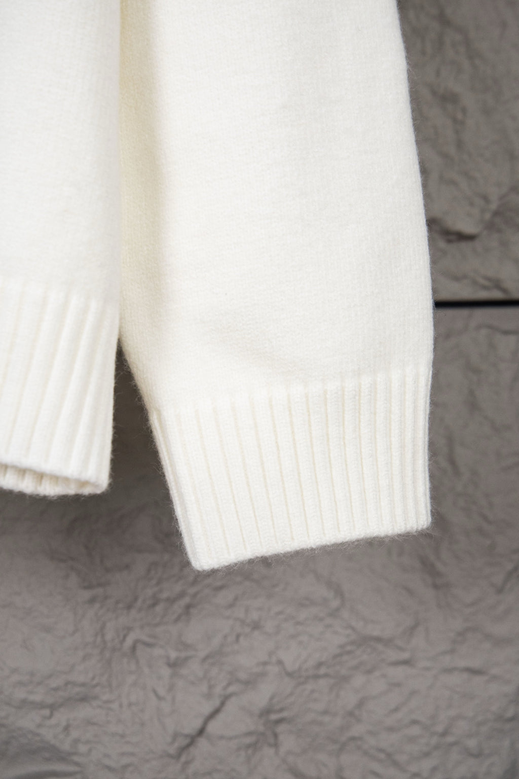 White knit sweater sleeve and lower hem with ribbed vertical knit panels