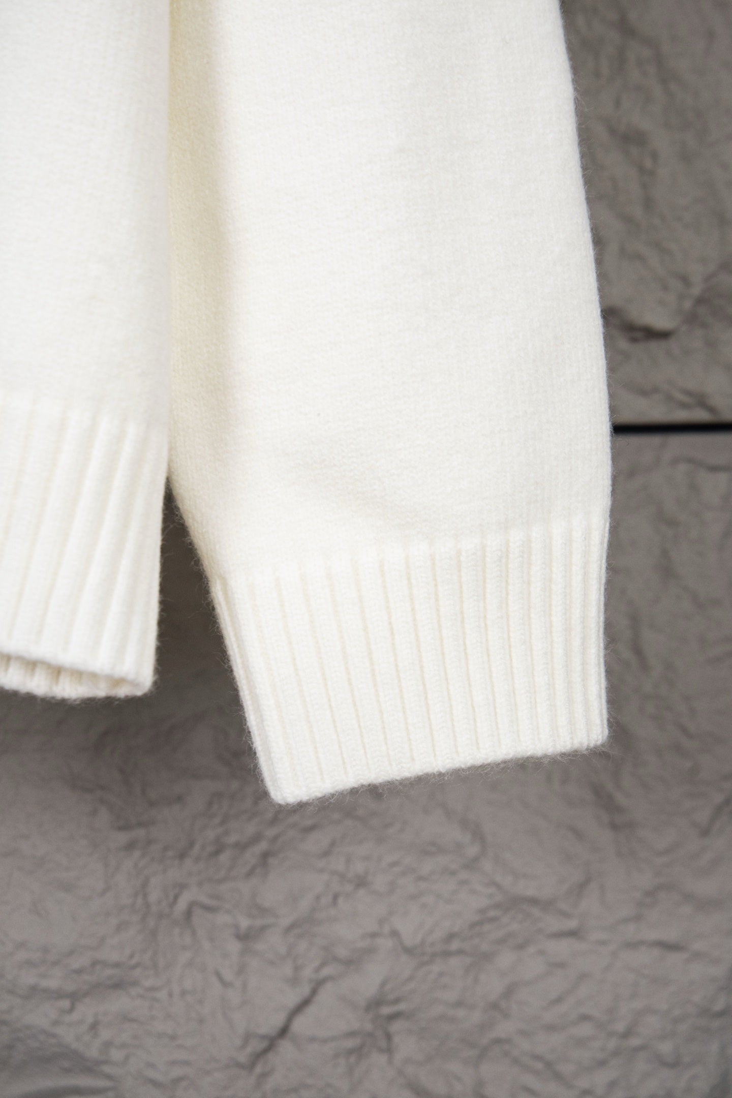 White knit sweater sleeve and lower hem with ribbed vertical knit panels