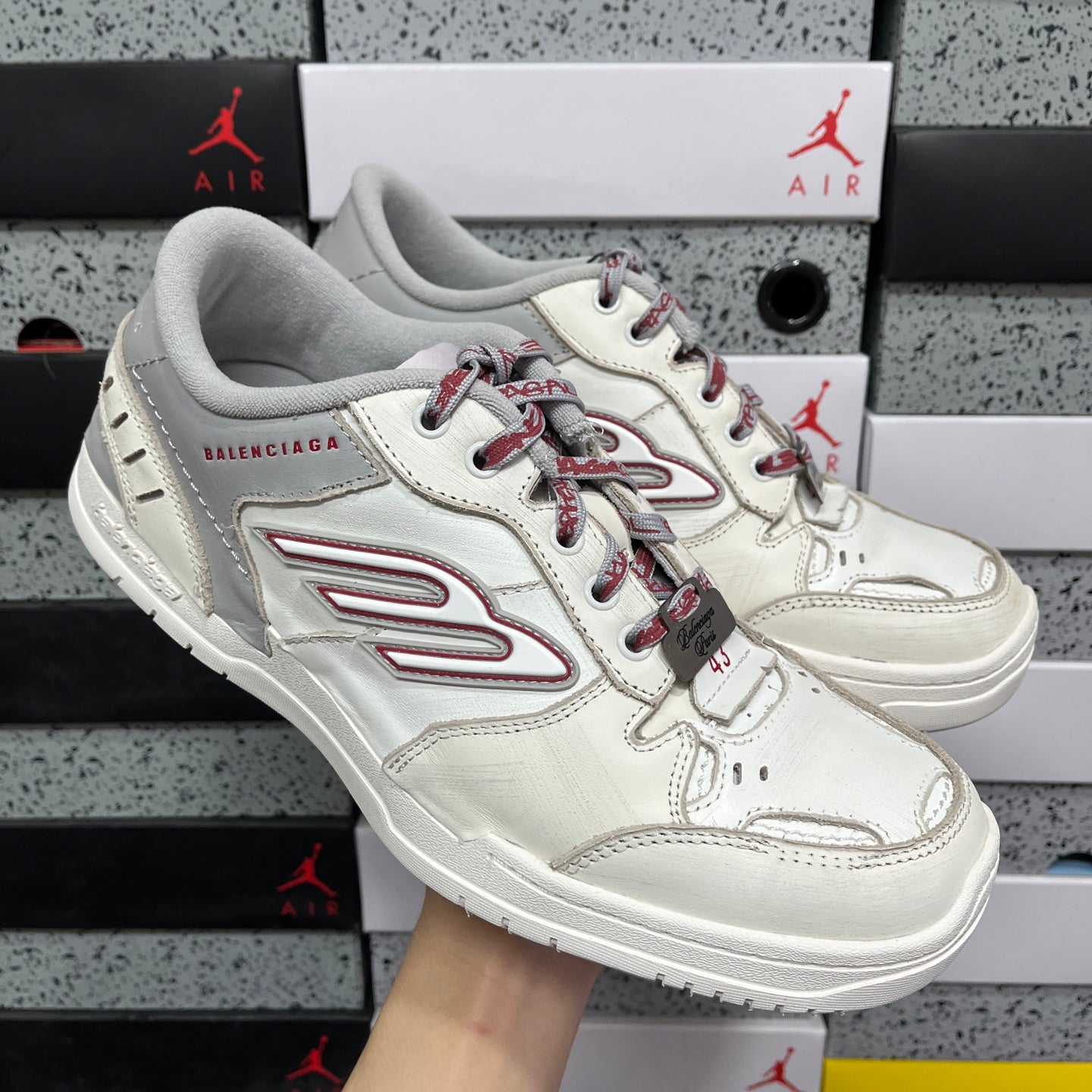 Angled view of white Balenciaga sneaker with red laces and red side logo stripe