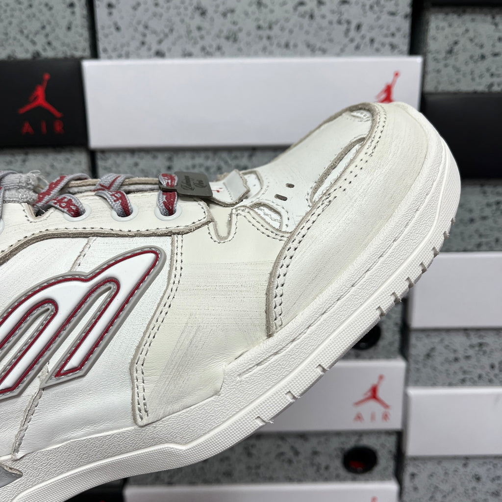 Side view of white Balenciaga sneaker with red stripe logo and textured stitching