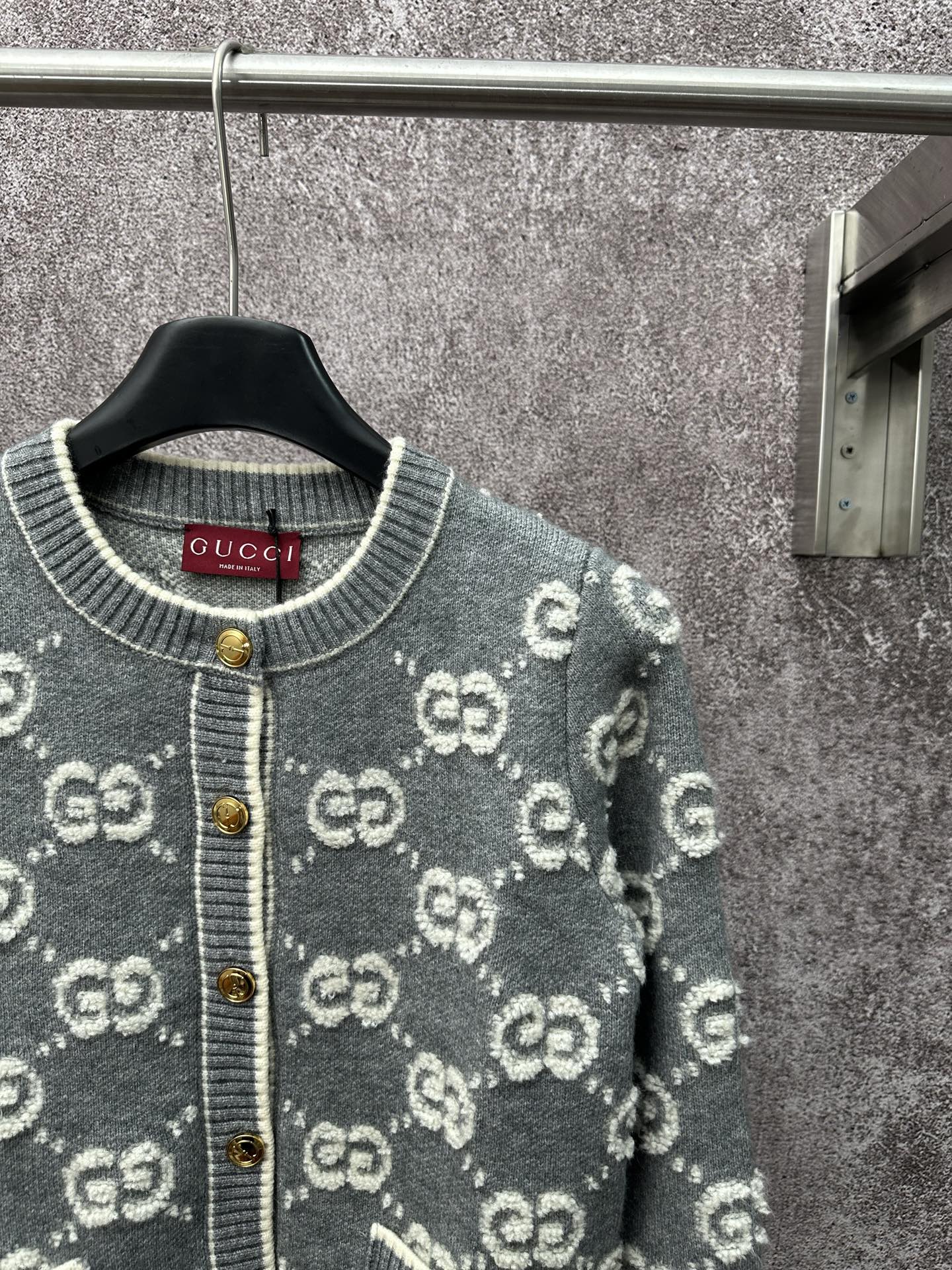 Gucci dark green cardigan close-up with GG pattern, ribbed collar, and gold snap buttons.