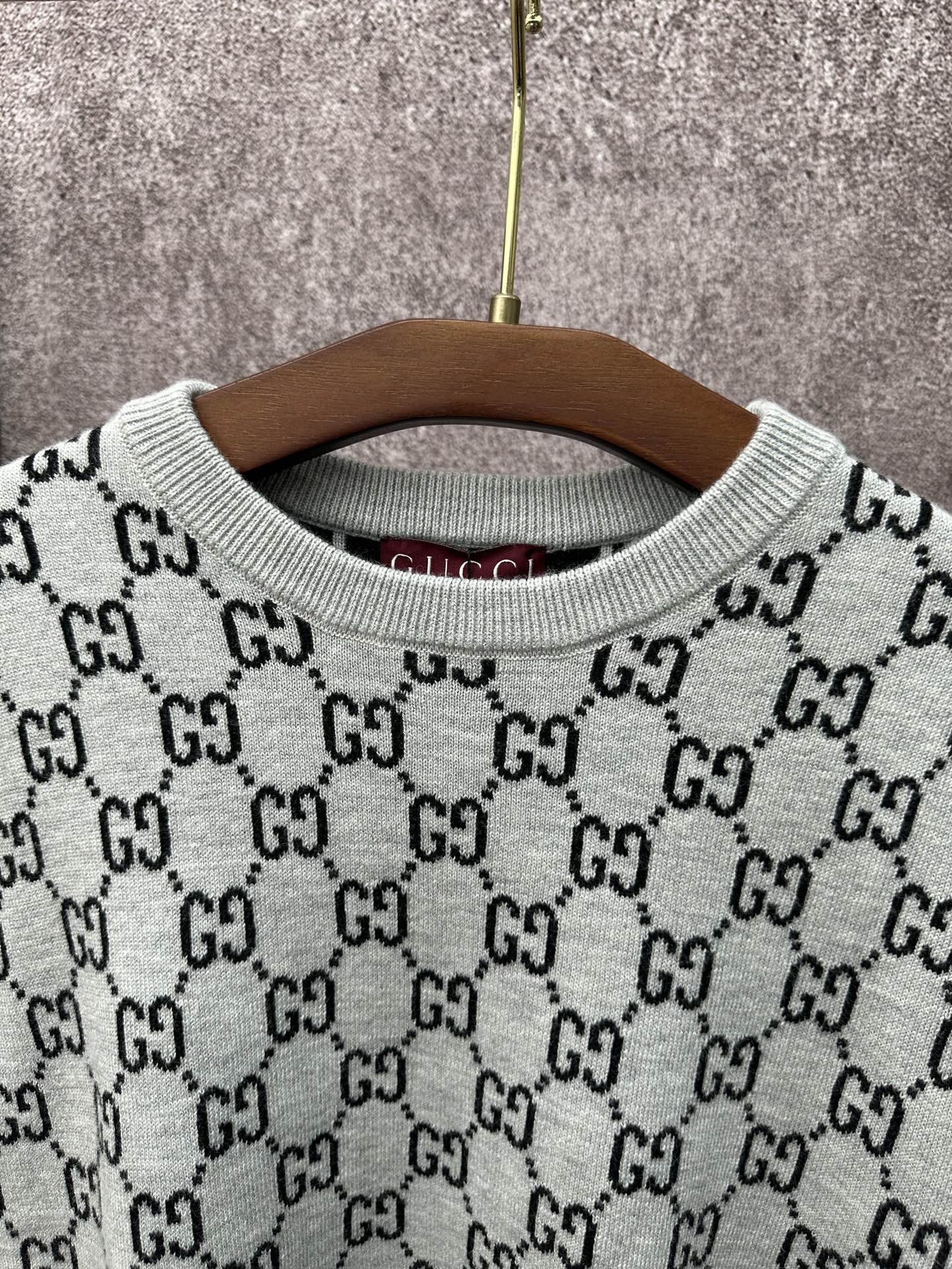 Light gray knit T-shirt close-up: ribbed crew neck with black GG logo pattern