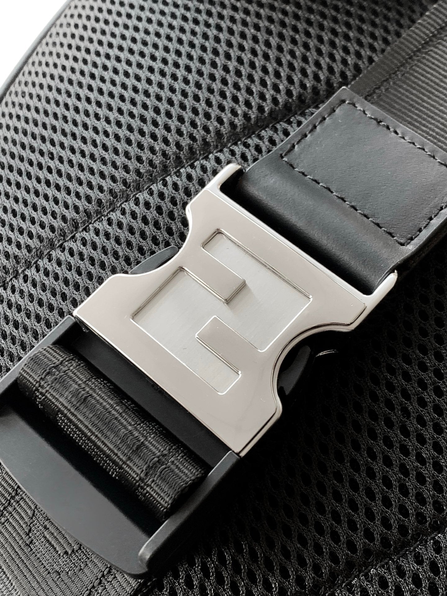 Fendi bag belt-style buckle hardware on mesh-textured panel with black stitching details.