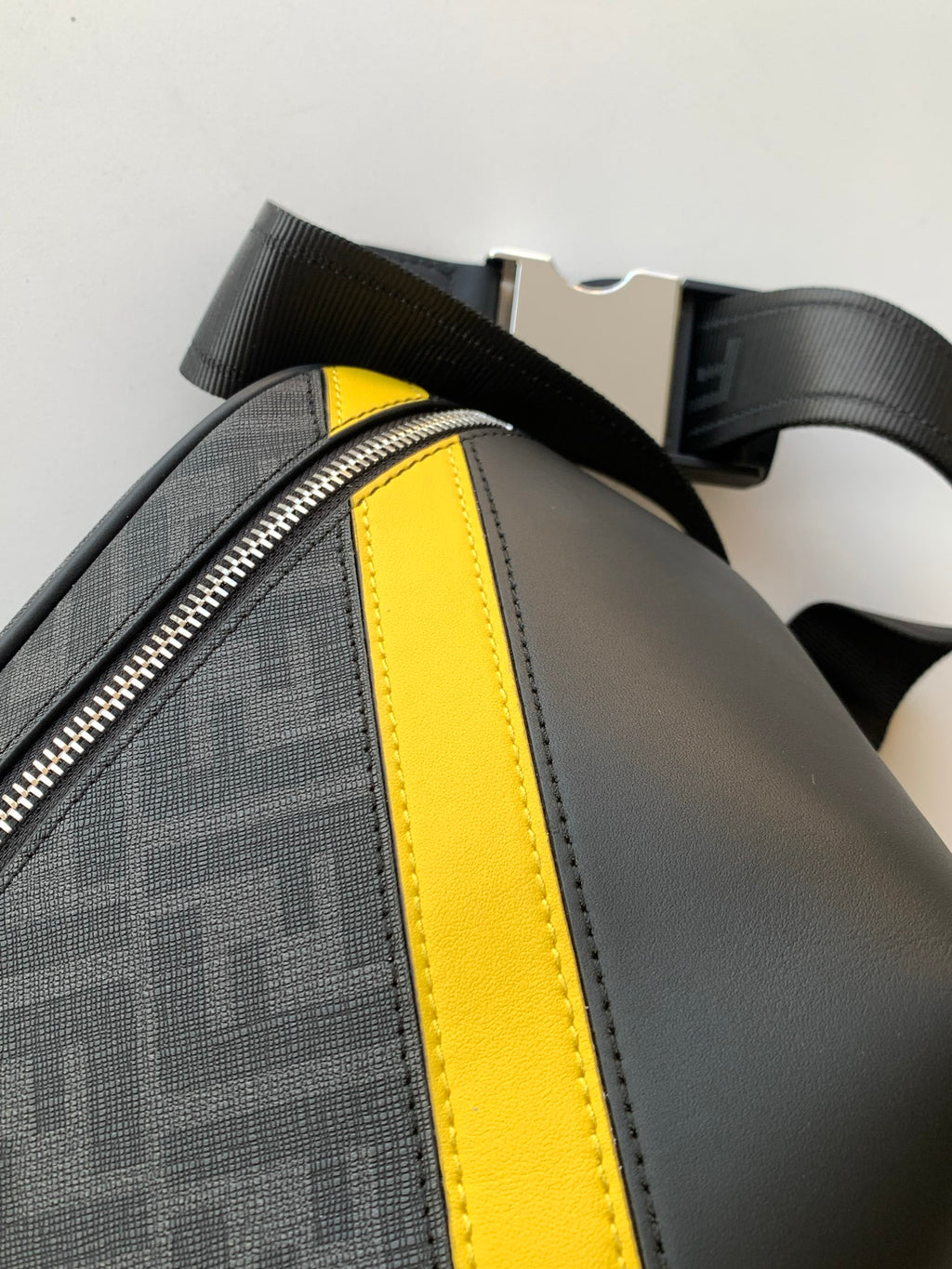Fendi bag side view with neon yellow trim stripe, textured fabric, and adjustable shoulder strap.