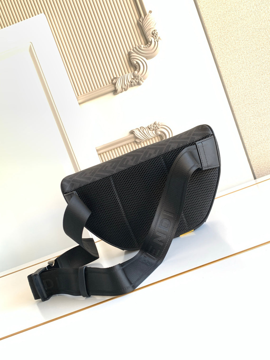 Fendi bag with dark mesh-like panel, curved side, neon yellow stripe, and wide crossbody strap.
