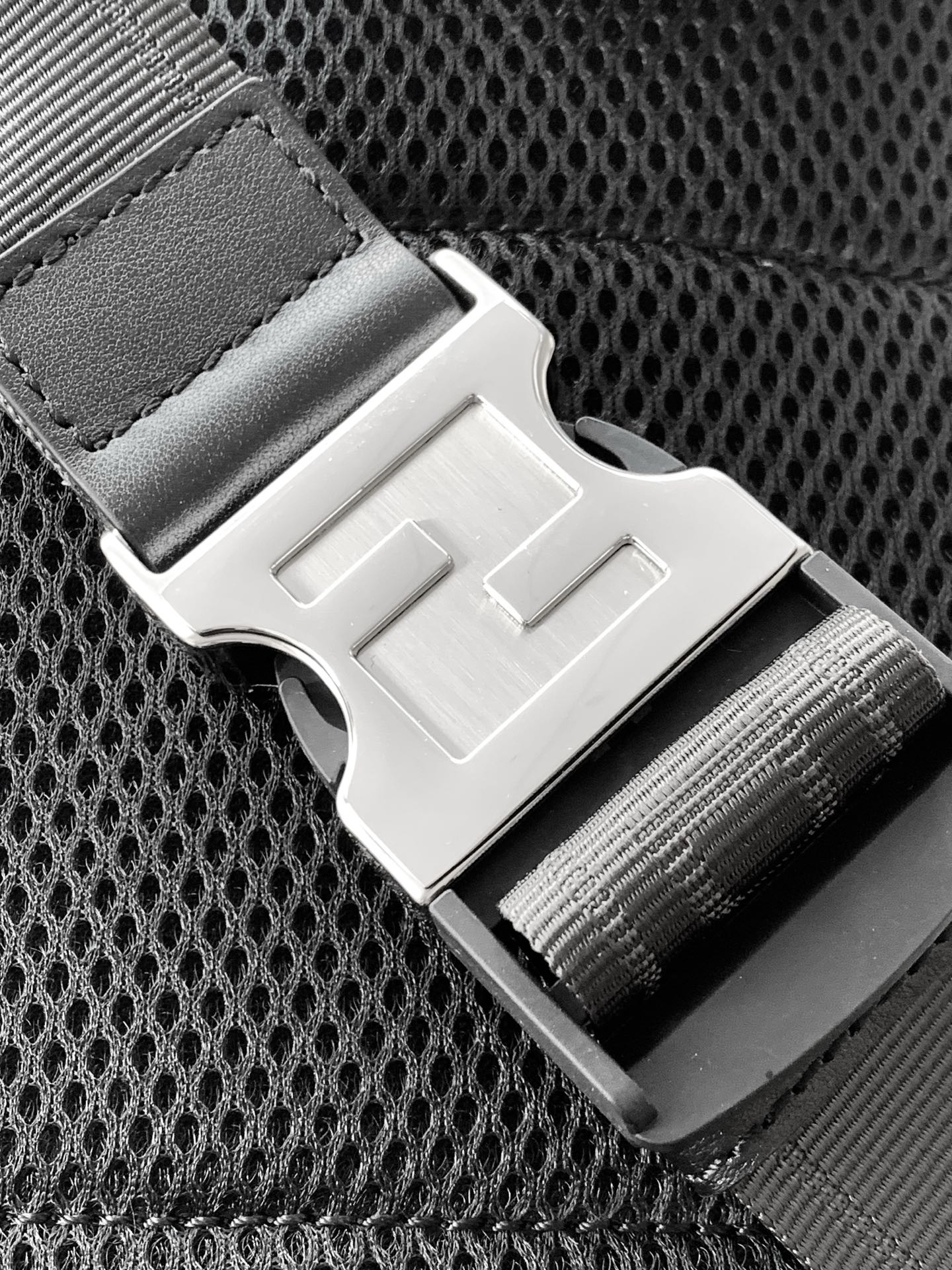 Fendi crossbody bag detail with metal buckle strap and textured dark mesh panel