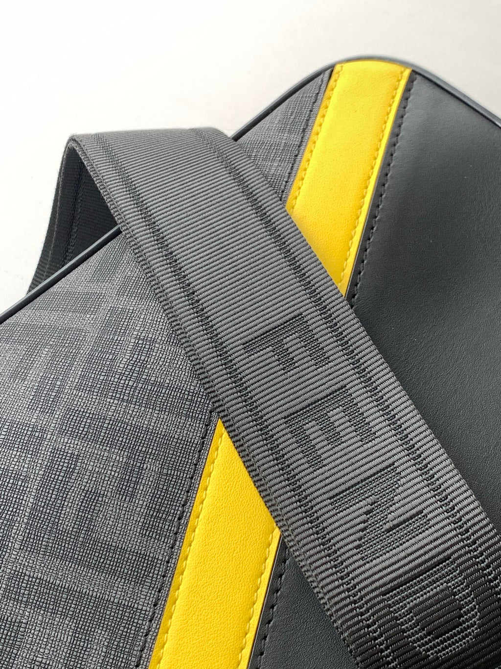 Fendi bag close-up: striped fabric panel with yellow leather trim and stitched edging