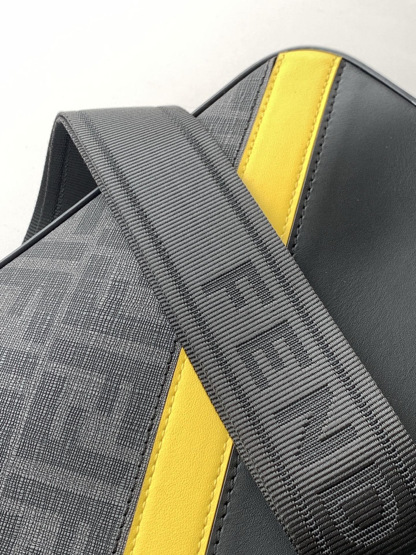 Fendi bag close-up: striped fabric panel with yellow leather trim and stitched edging