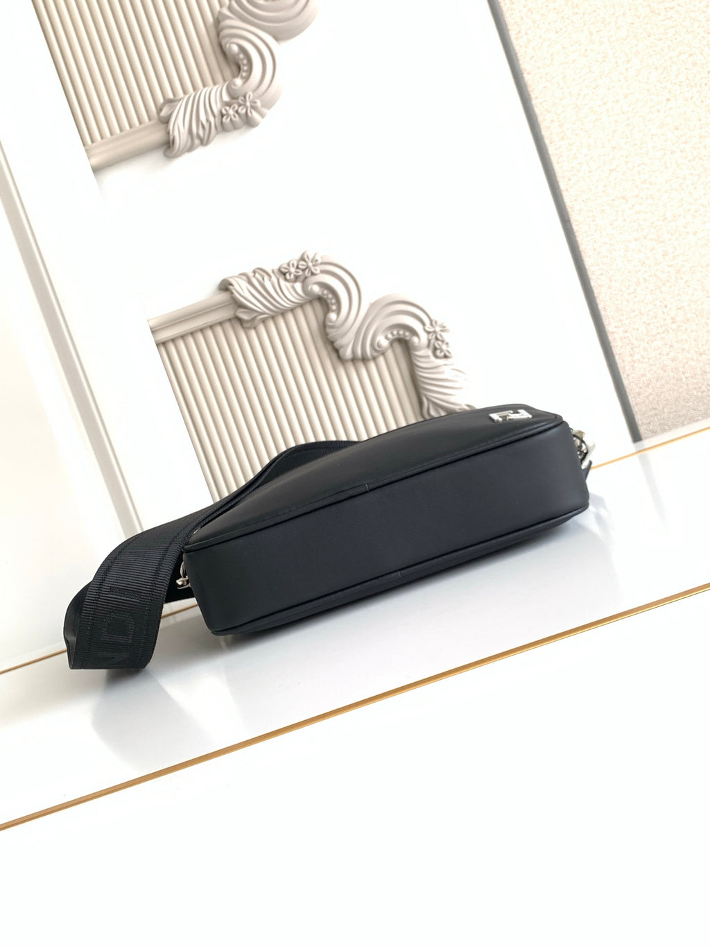 Fendi black long-strap bag lying on side, zip closure and silver rings