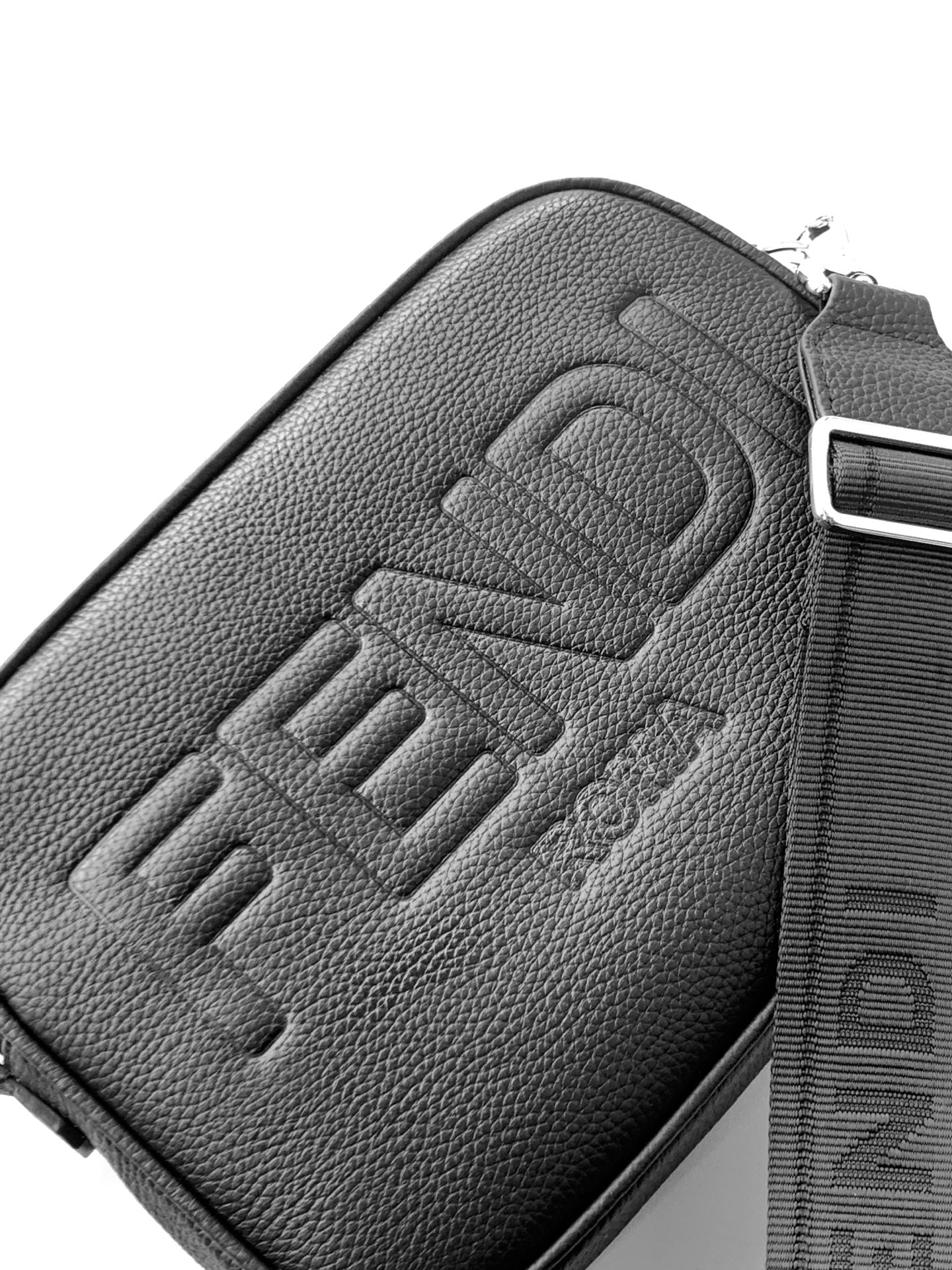 Fendi bag close-up: embossed FENDI logo on dark textured leather with zip trim.