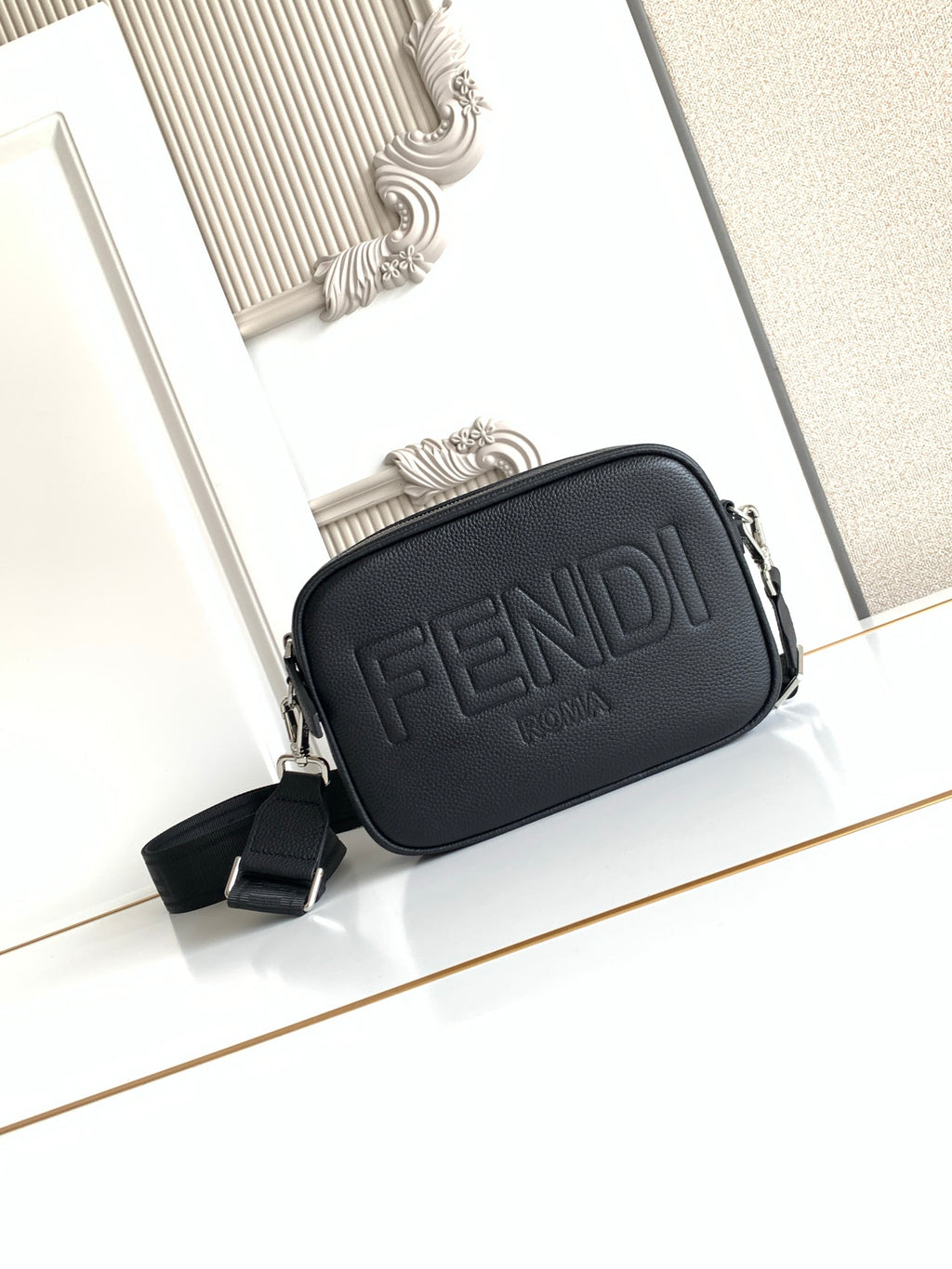 Fendi crossbody bag in dark textured leather with embossed FENDI logo and zip top.