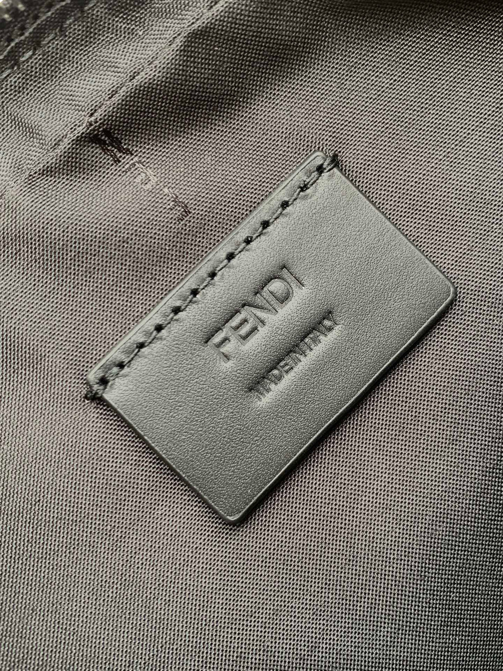Fendi logo patch close-up on dark fabric lining with stitched edge and embossed FENDI.