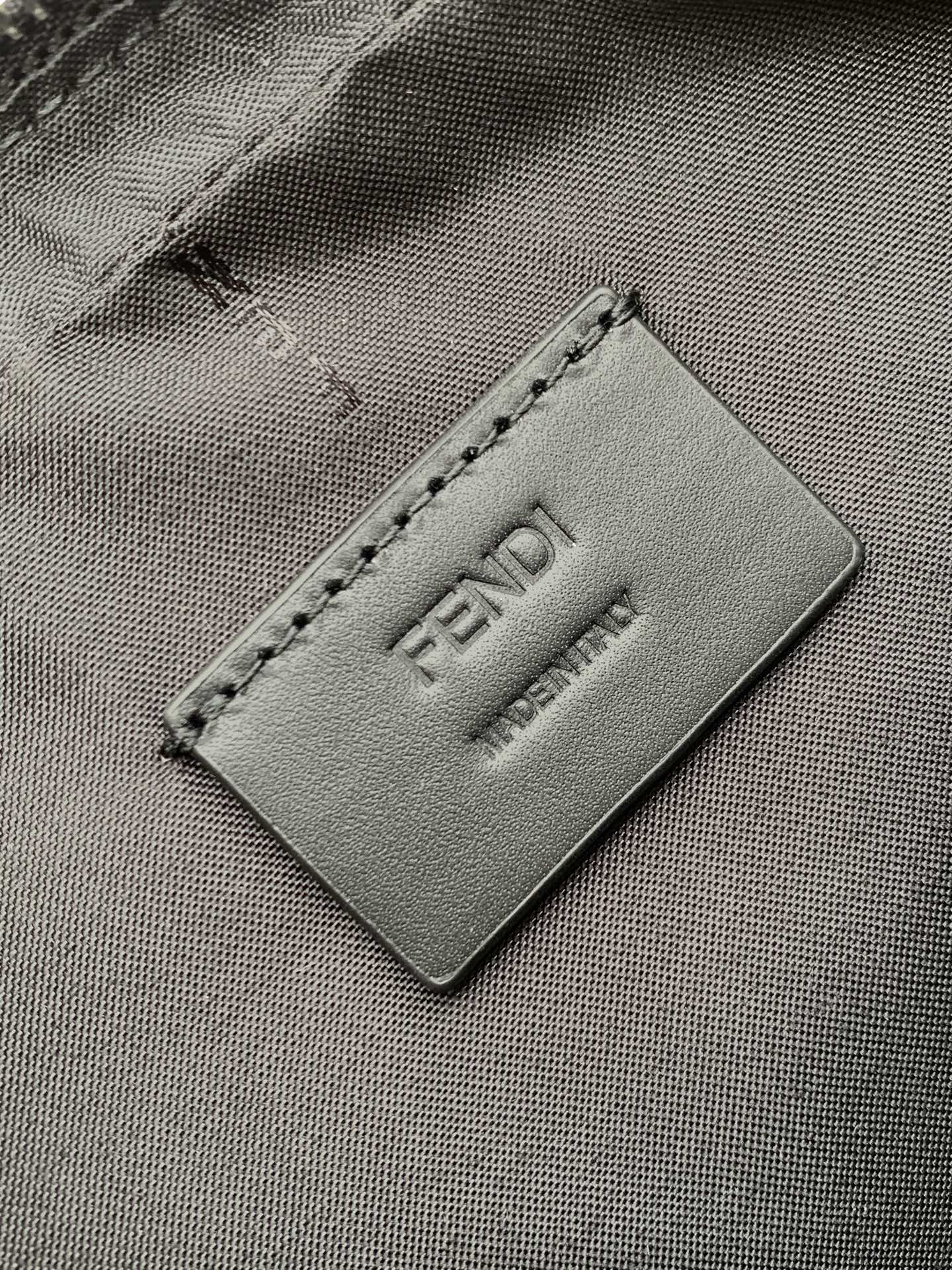 Fendi logo patch close-up on dark fabric lining with stitched edge and embossed FENDI.