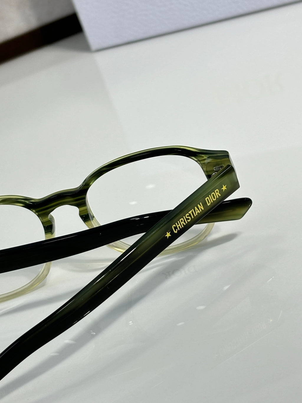 Dior eyeglasses close-up: green temple arm with logo lettering