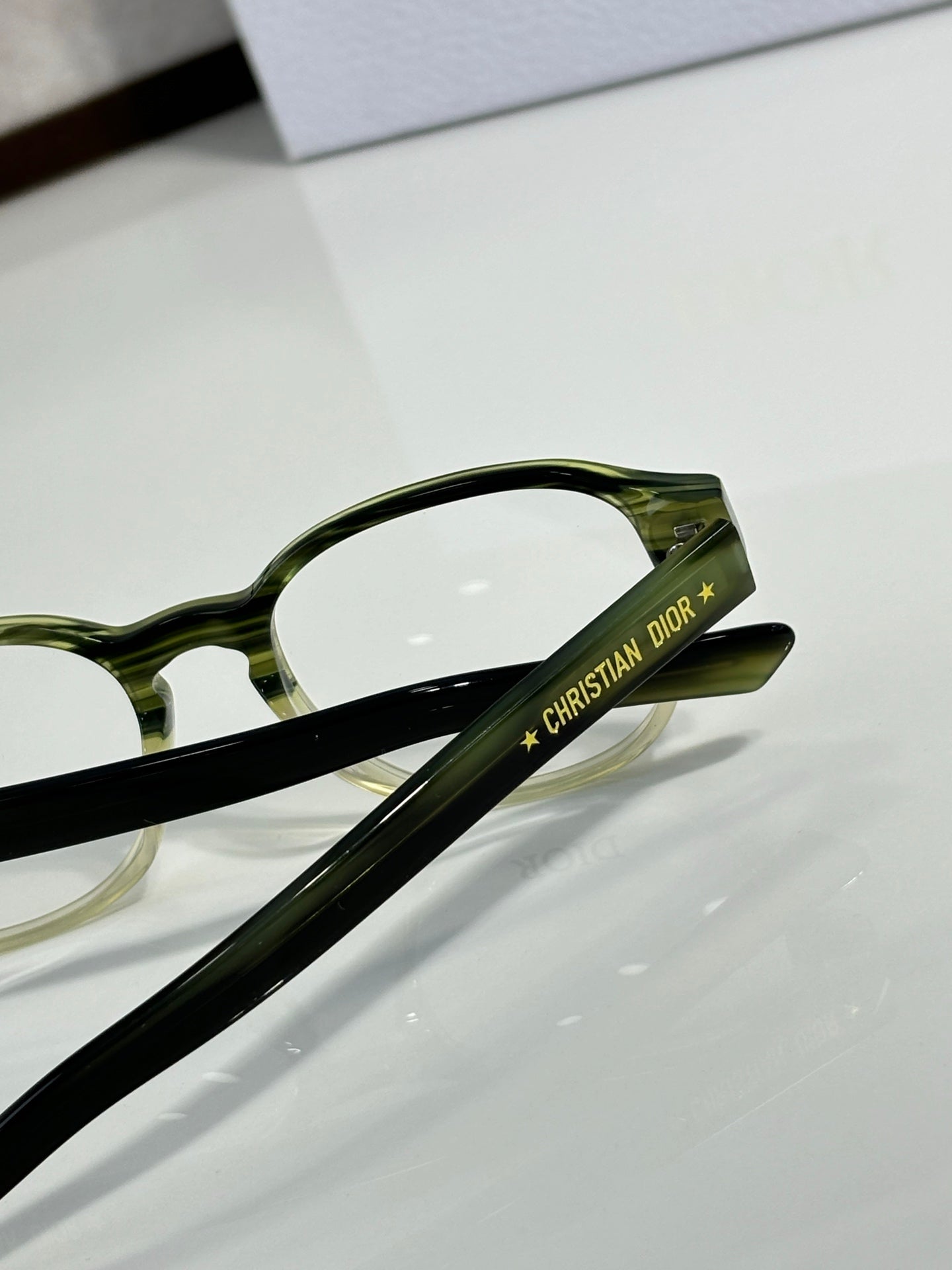 Dior eyeglasses close-up: green temple arm with logo lettering