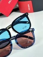 Stacked sunglasses with blue and brown lenses; dark frames with gold accents.