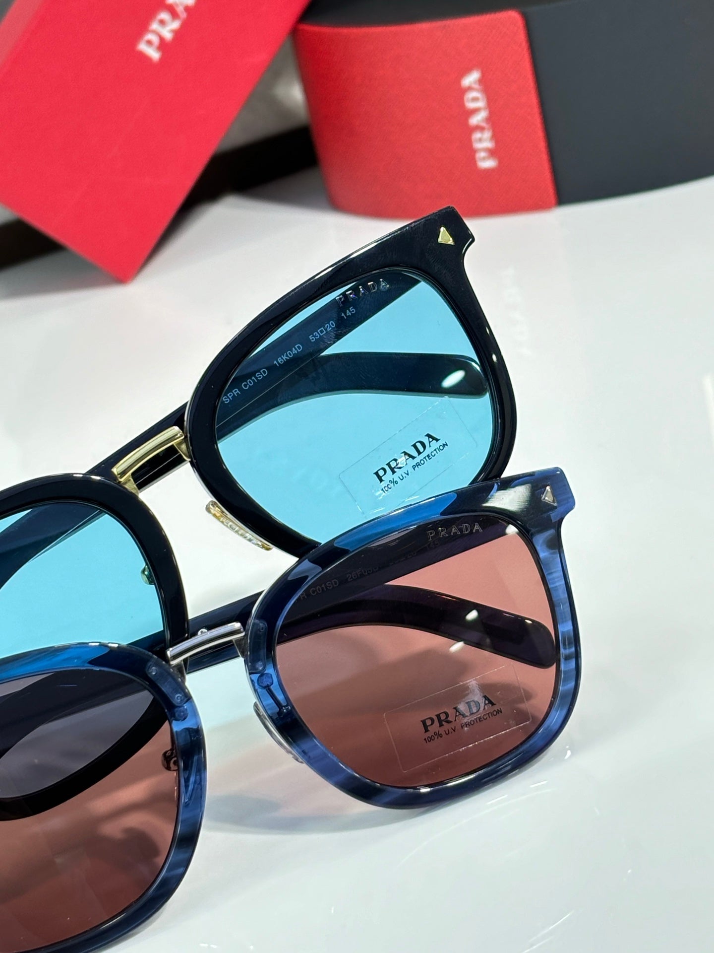 Stacked sunglasses with blue and brown lenses; dark frames with gold accents.
