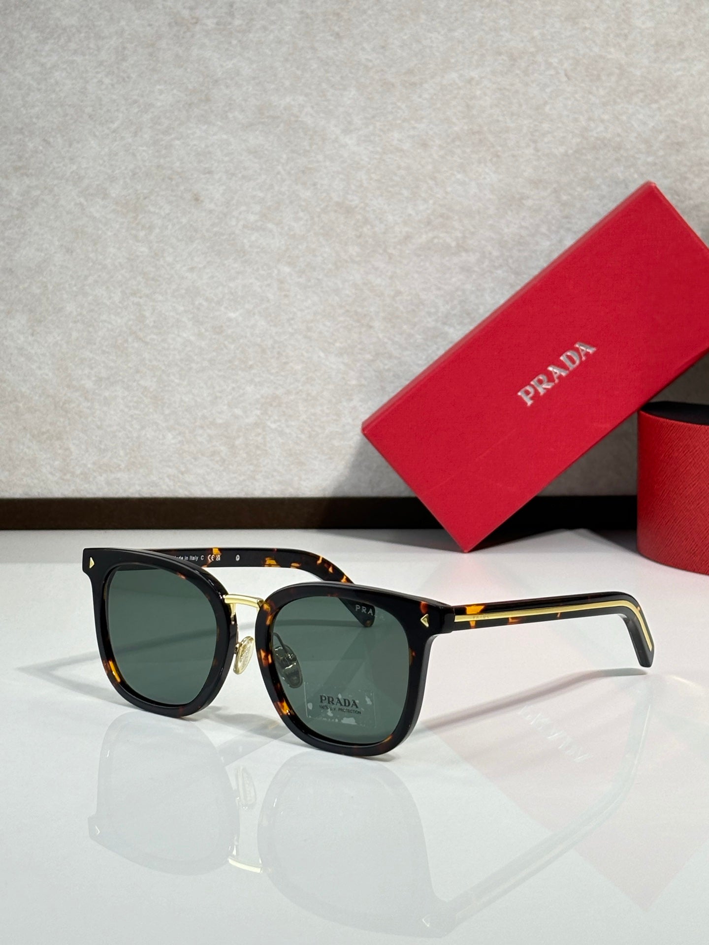 Tortoiseshell-and-gold sunglasses with greenish lenses and rounded frames.