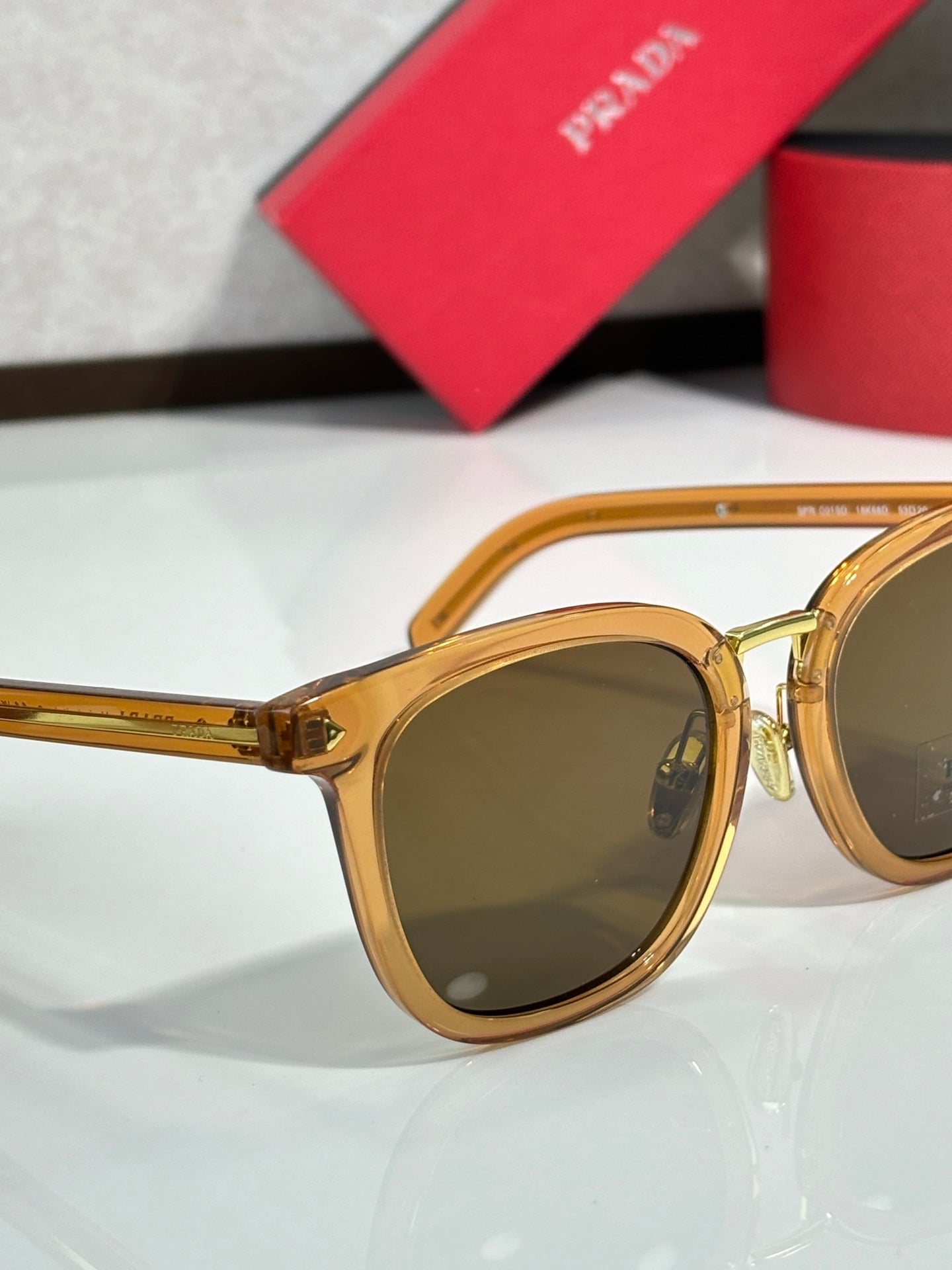 Gold sunglasses with amber-brown lenses and rounded frame with curved temples.