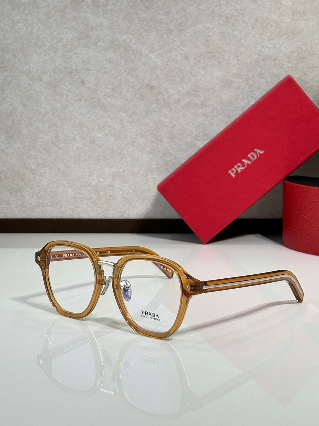 Prada eyeglasses with light tan round frames and clear lenses, logo on front.