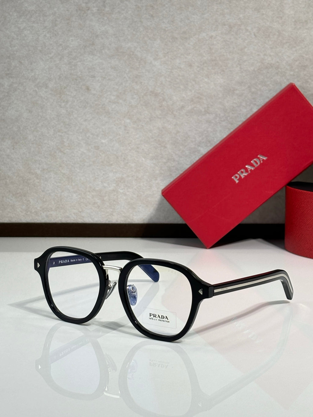 Prada eyeglasses with black round frames and clear lenses, side arms with logo.
