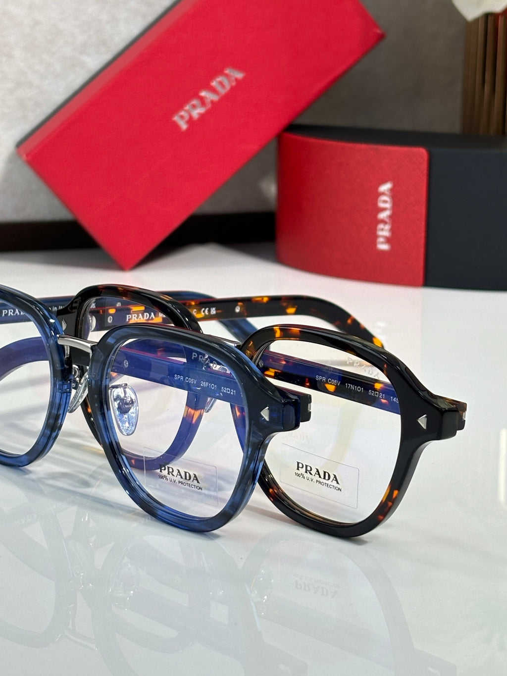 Prada eyeglasses with multicolor round frames and clear lenses, PRADA logo on lenses.