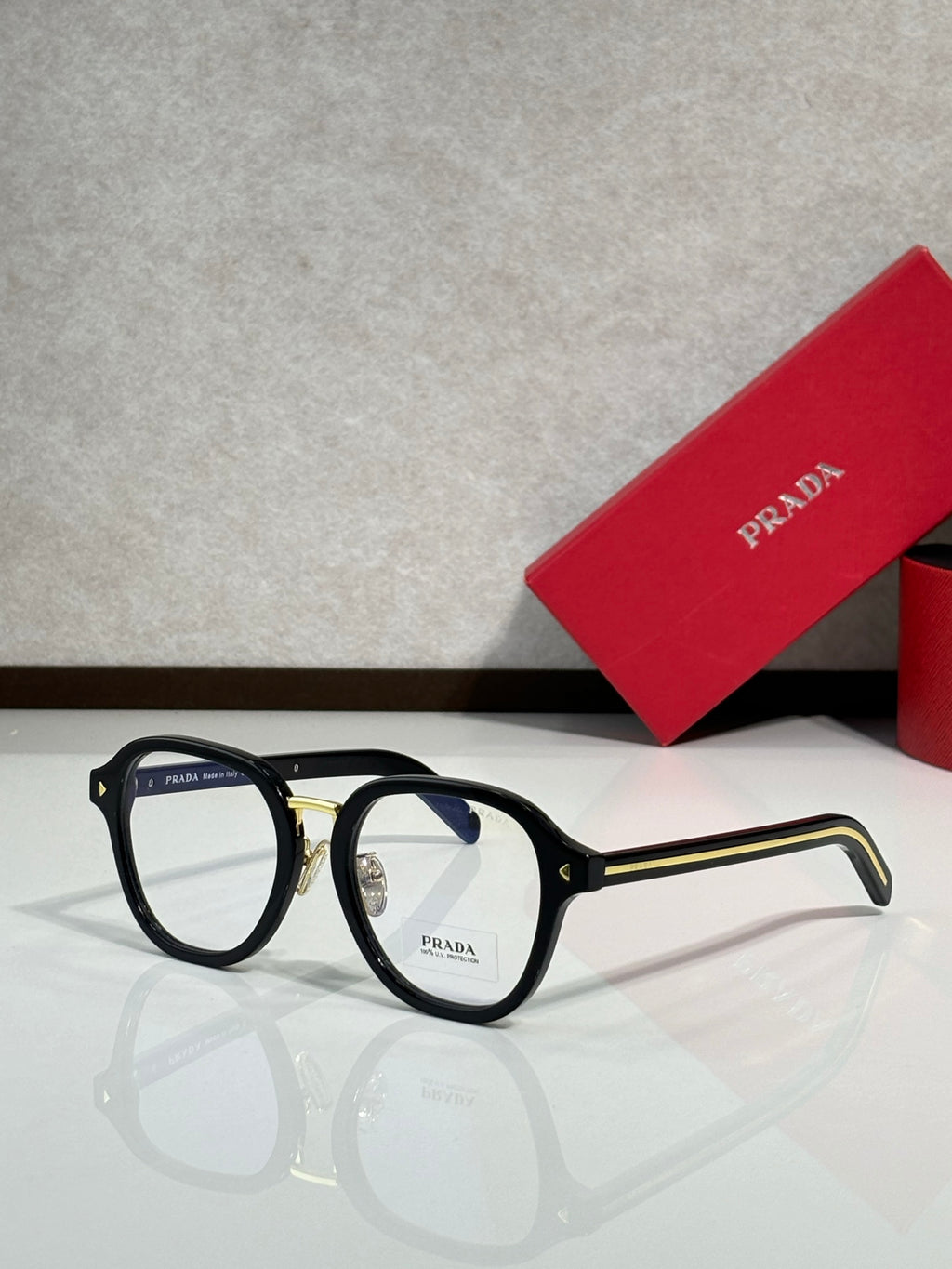 Prada eyeglasses with black round frames and clear lenses, dark logo on temple.
