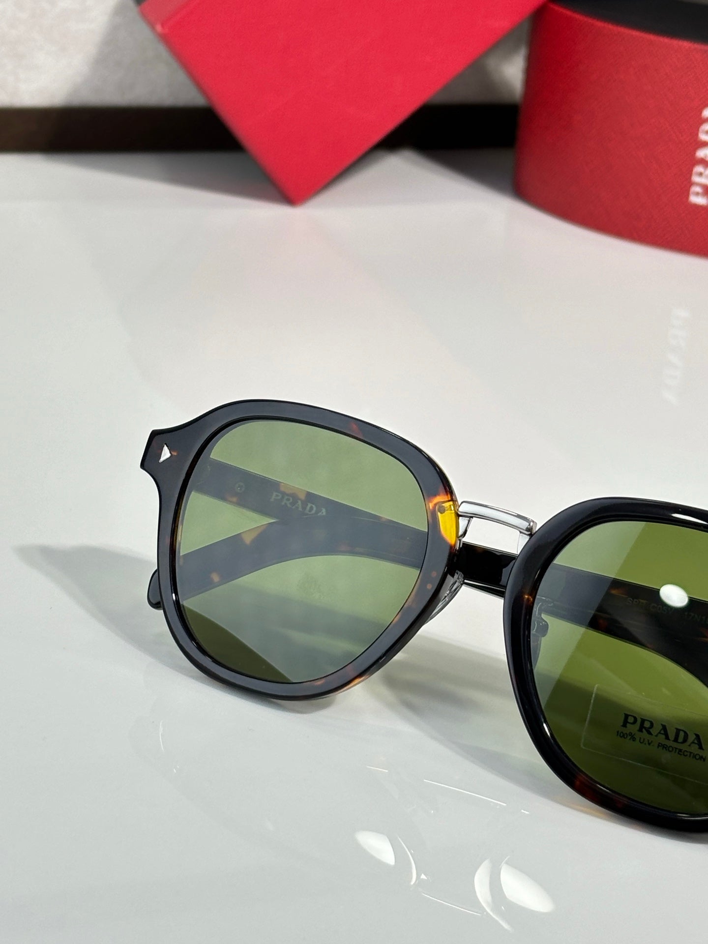 Prada black round eyeglasses with green-tinted lenses and side logo